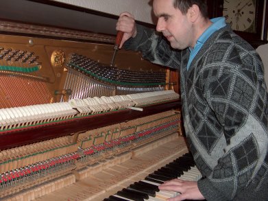 picture of piano tuner working on piano